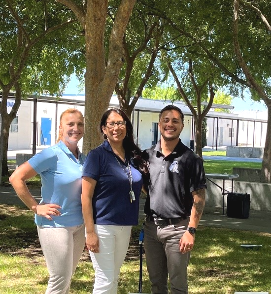 three people standing underneath tree smiling